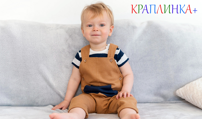 Дитина 3 років сидить на дивані у себе в квартирі