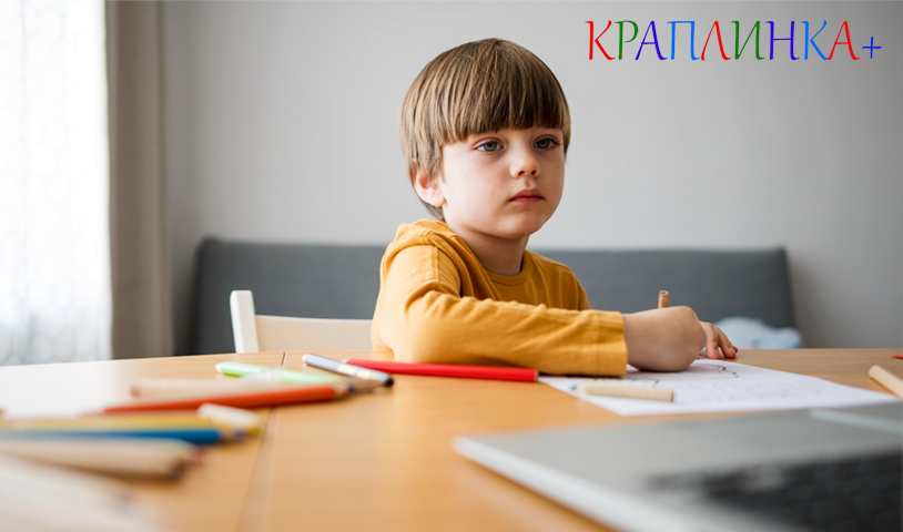 дитина спокійно сидить за столом і виконує завдання